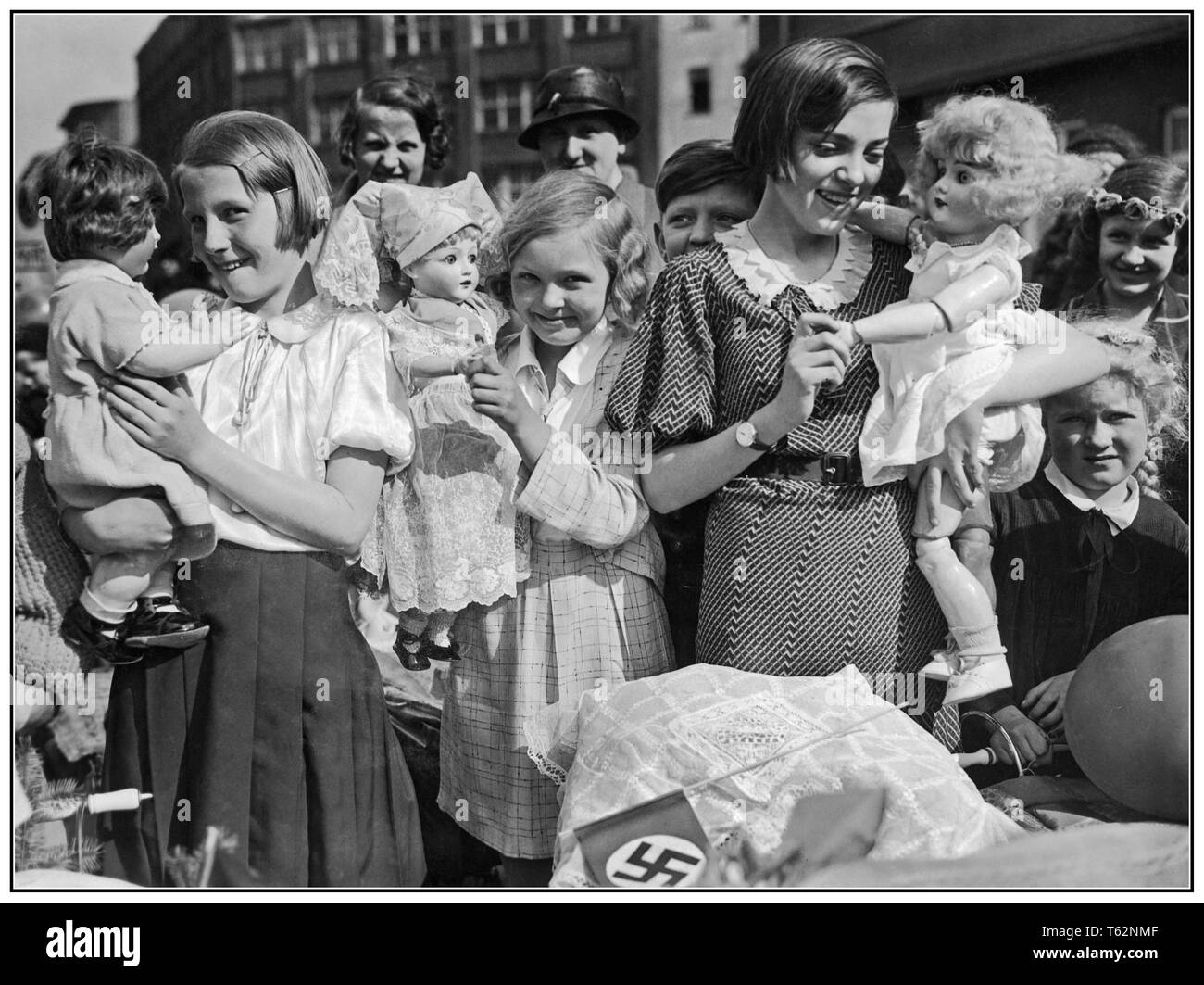Vintage Nazi Propaganda Bild einer Gruppe von Deutschen Mädchen mit Puppen und Kinderwagen, mit hakenkreuzfahne im Vordergrund. Sie bereiten sich auf die Mütter und Kinder Tag Prozession in Berlin Deutschland 1934 zu gehen Stockfoto