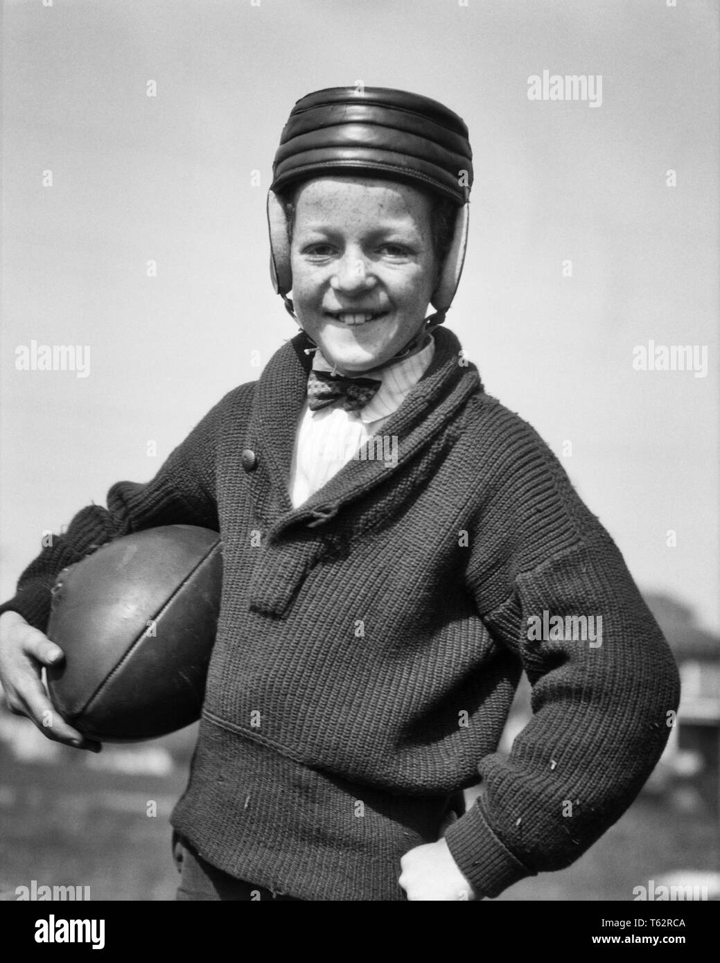 1920er lächelnd FRECKLE FACE JUGENDLICHE JUNGE TRAGEN FRÜH LEDER Helm und Schal - STEHKRAGEN PULLOVER HOLDING FUSSBALL AUF KAMERA-b 1806 HAR 001 HARS GESICHTSBEHANDLUNG STIL GESUNDE SICHERHEIT LEADER-WETTBEWERB ATHLET ENTSPANNENDE FREUDE FREUDE LIFESTYLE ZUFRIEDENHEIT FEIER BEREIT LÄNDLICHE GESUNDHEIT HOME LIFE LEICHTATHLETIK KOPIE RAUM mit halber Länge körperliche Fitness INSPIRATION MÄNNER ATHLETISCHE GROBE VERTRAUEN AUSDRÜCKE B&W AUGENKONTAKT ZIELE ERFOLG SKILL AKTIVITÄT AMUSEMENT GLÜCK PHYSISCHEN FRÖHLICHEN ANFANG HOBBY SCHUTZ STÄRKE STILE SIEG STRATEGIE MUT, INTERESSE UND MEISTER WAHL AUFREGUNG HOBBYS Stockfoto