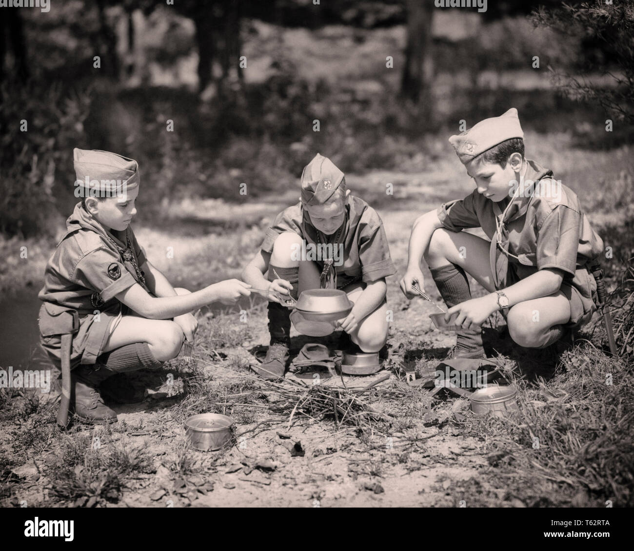 1950er Jahre drei PFADFINDER Kochen über dem Lagerfeuer-b 6086 HAR 001 HARS UNIFORMEN BOY SCOUT VERBINDUNG THRIFTY ZUVORKOMMEND freundliche und hilfsbereite Art REVERENT UNTERSTÜTZUNG VERTRAUENSWÜRDIG PFADFINDER ZUSAMMENARBEIT Wachstum von Jungfischen treu vor - jugendlich PRE-TEEN BOY SCOUTING ZWEISAMKEIT SCHWARZ UND WEISS BRAVE KAUKASISCHEN ETHNIE HAR 001 GEHORSAM ALTMODISCH Stockfoto