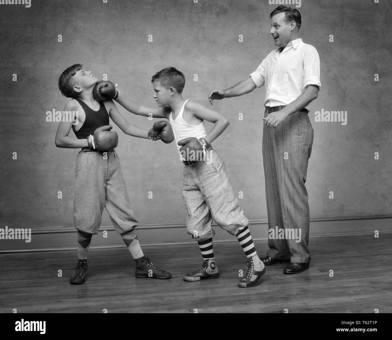 1930er Jahre zwei jungen SPARRING STANZEN BOXHANDSCHUH SPORTLICHE OUTFITS ERWACHSENEN MANN ALS SCHIEDSRICHTER-b 8259 HAR 001 HARS ATHLETIK KOPIE RAUM VOLLER LÄNGE KÖRPERLICHE FITNESS PERSONEN MÄNNER RISIKO ATHLETISCHE HANDELN B&W ABENTEUER SCHUTZ STÄRKE AUFREGUNG OUTFITS ERHOLUNG STANZEN VERBINDUNG ATHLETEN ZUSAMMENARBEIT jugendliche Mitte - Mitte - erwachsenen Mann SPAR SPARRING SCHWARZ UND WEISS KAUKASISCHEN ETHNIE HAR 001 ALTMODISCH Stockfoto