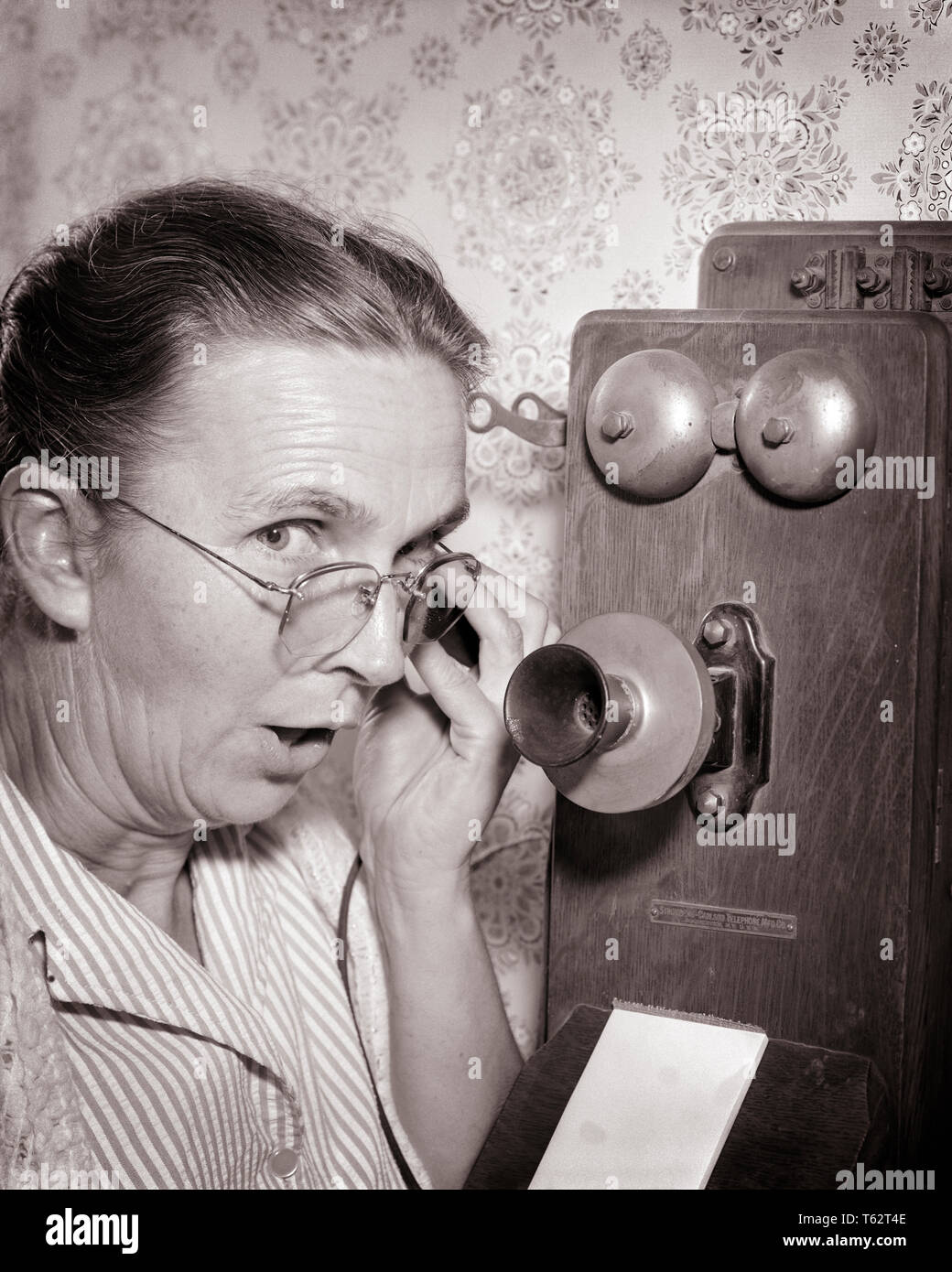 1930er Jahre 1940er Jahre ältere, reife Frau auf Kamera sprechen klatschen auf ALTMODISCHE HOLZ- KURBEL WAND TELEFON-bt 00141 CAM001 HARS KOMMUNIKATION KOPIEREN PLATZ DAMEN PERSONEN VERTRAUEN BRILLEN KLATSCHEN älterer Erwachsener mittleren Alters B&W AUGENKONTAKT SENIOR FRAU Frau mittleren Alters OLDSTERS KOPF UND SCHULTERN ALTEM AUFREGUNG FORTSCHRITTE ERHOLUNG CAM001 TELEFONE ÄLTESTEN ANSCHLUSS TELEFONE SCHWARZ UND WEISS KAUKASISCHEN ETHNIE ALTMODISCHE ALTMODISCHE Verdächtige in der Wand Stockfoto