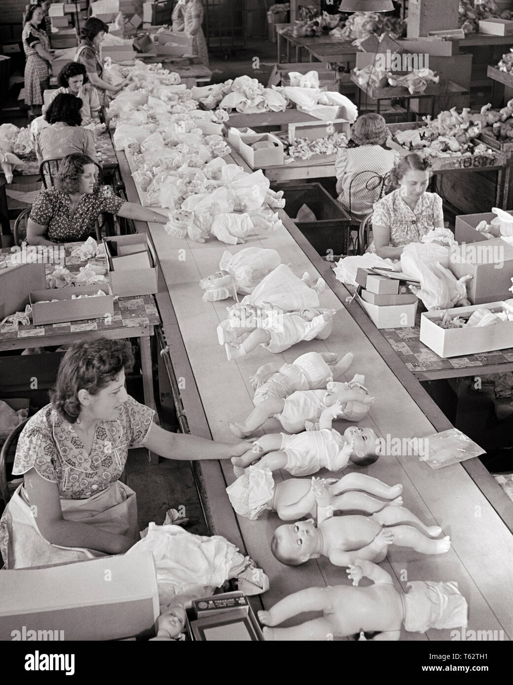 1950 FRAUEN ARBEITEN AM MONTAGEBAND DOLL FACTORY DRESSING DIE PUPPEN ZU SETZEN IN KARTONS - ich 1273 LAN001 HARS BESCHÄFTIGUNG DER ARBEITSKRÄFTE VERARBEITENDE BERUFE VERPACKUNG KONZEPTIONELLE MITARBEITER BABY DOLL BABY PUPPEN ZUSAMMENARBEIT PUPPENKLEIDER HERSTELLUNG Mitte - Mitte - ERWACHSENE FRAU SCHWARZ UND WEISS KAUKASISCHEN ETHNIE FABRIKEN ARBEITENDEN ALTMODISCH Stockfoto