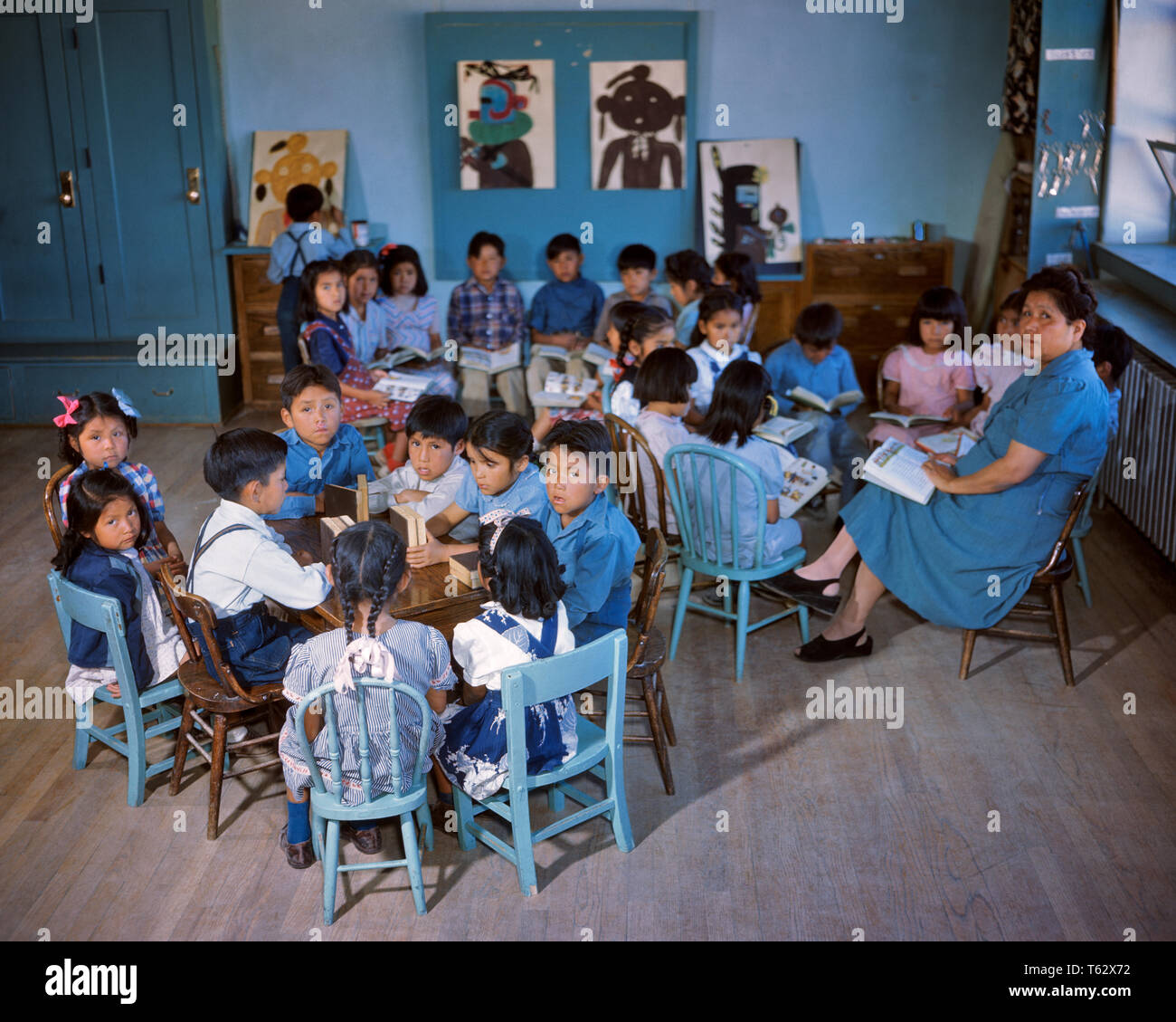 1950 NAVAJO INDIANERRESERVAT SCHÜLERINNEN UND SCHÜLER jungen Mädchen sitzen in blaue Stühle an Tischen, die Lehrerin Frau Klassenzimmer - ki 295 DEL 001 HARS KOPIE RAUM MIT HALBER LÄNGE DAMEN PERSONEN SITZEN INDIANER ERWACHSEN VEREINIGTE STAATEN VON AMERIKA MÄNNER NAVAJO WESTERN AMERIKANER TABELLEN NORDAMERIKA NORDAMERIKA SCHULEN MENSCHEN GESCHICHTE GRAD HOHEN WINKEL BERUFE PRIMÄR RESERVIERUNG NATIVE AMERICAN K-12 GRUNDSCHULE JUGENDLICHE MITTE NACH MITTE DER ERWACHSENEN FRAU INDIANER INDIGENE ALTMODISCHE FRAUEN Stockfoto