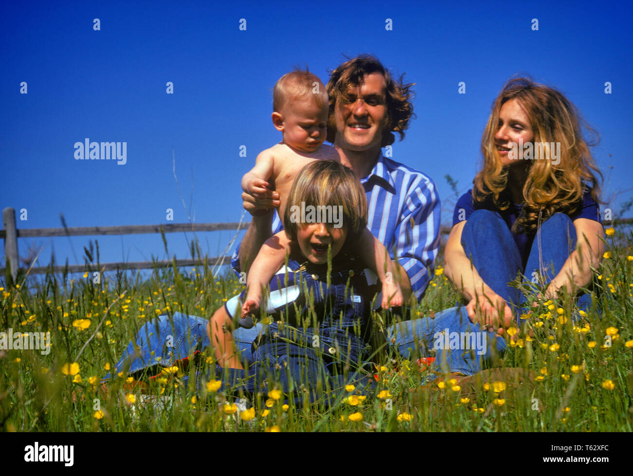 1970er lächelt glücklich HIPPIE vierköpfige Familie Vater Mutter Kind und  Baby Kinder sitzen gemeinsam IM FRÜHJAHR FELD VON WILDBLUMEN - KJ 6287 HAR  001 HARS EHEMANN VATER VIER MOM KLEIDUNG GESICHTER NOSTALGISCHE