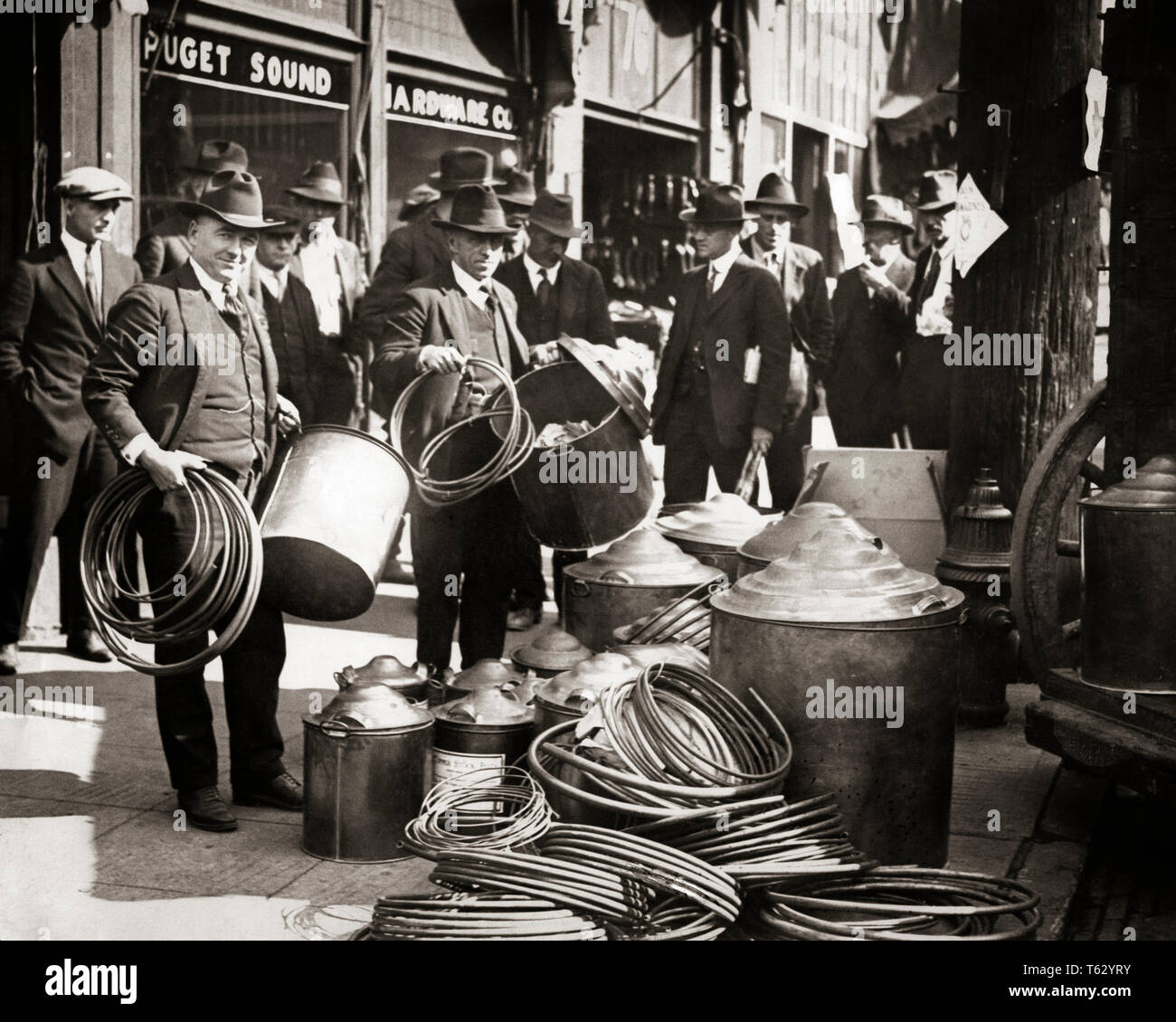 1920er Jahre 1930er Jahre EINNAHMEN AGENTEN RAID-HARDWARE STORE DISPLAY GEGENSTÄNDE BESCHLAGNAHMT FÜR ALKOHOL NOCH WÄHREND VERBOT SEATTLE WASHINGTON - Q2008 CPC 001 HARS ANZEIGE IN VOLLER LÄNGE PERSONEN MÄNNER RISIKO IM MITTLEREN ALTER B&W REGIERUNG TRAURIGKEIT Mann mittleren Alters AUGENKONTAKT ERFOLG VERSUCHUNG Anzug und Krawatte ABENTEUER TRINKEN ENTDECKUNG REIHEN SCHUTZ STÄRKE SIEG STRATEGIE MUT BEGEISTERUNG FÜHRUNG FORTSCHRITTE VERBOT AUTORITÄT BERUFEN POLITIK RAID-HARDWARE WESTEN KONZEPTIONELLE AGENTEN WASSERKESSEL MOONSHINE STILLS KUPFER illegale Mitte - Mitte - erwachsenen Mann EINNAHMEN ZWEISAMKEIT VOLSTEAD ACT junger erwachsener Mann AGENT Stockfoto