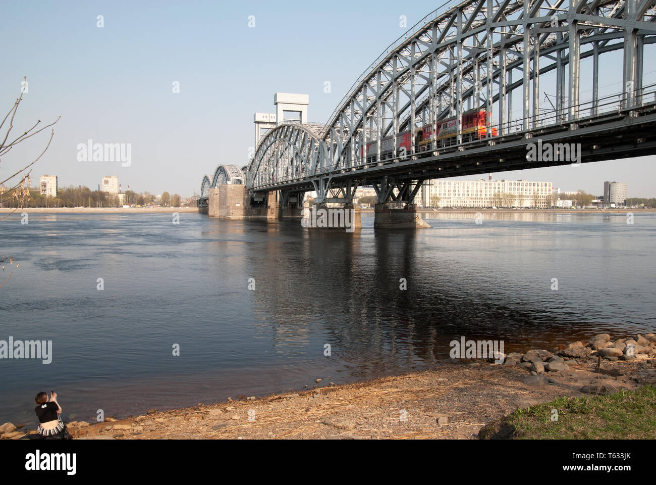 SAINT-Petersburg, Russland - 26 April 2019: Das Mädchen nimmt Bilder des Zuges nach Finnland Eisenbahnbrücke über den Fluss Neva in St. Petersburg Stockfoto