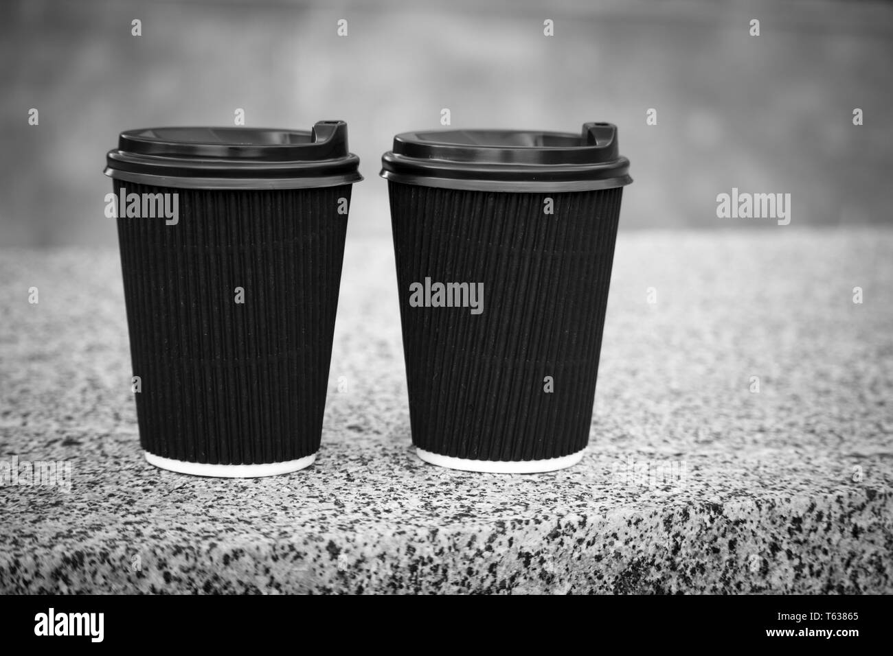 Zwei schwarze Einweg Tassen Kaffee mit Deckel stehen auf Die steinerne Brüstung, Rest und ein Spaziergang durch die Stadt, Hintergrund oder Konzept Stockfoto