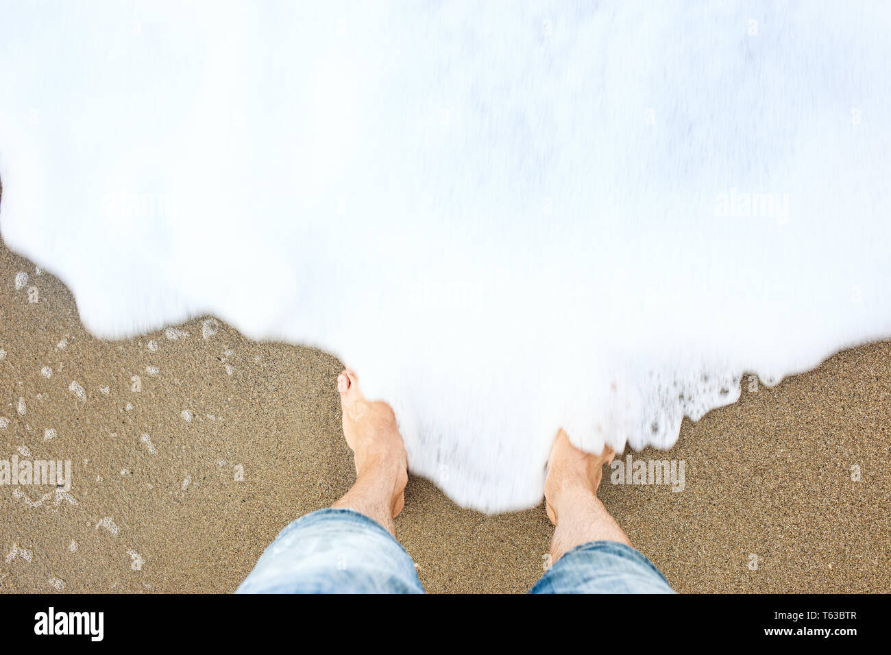 Der Mann mit den Füßen auf dem Sand an die Küste. Stockfoto