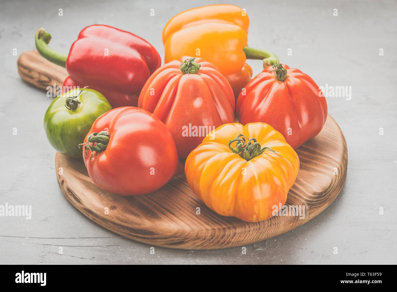 Auswahl an Bio große heirloom Tomaten und Paprika auf dem Holz, auf Grau konkreten Hintergrund, selektiver Fokus Stockfoto