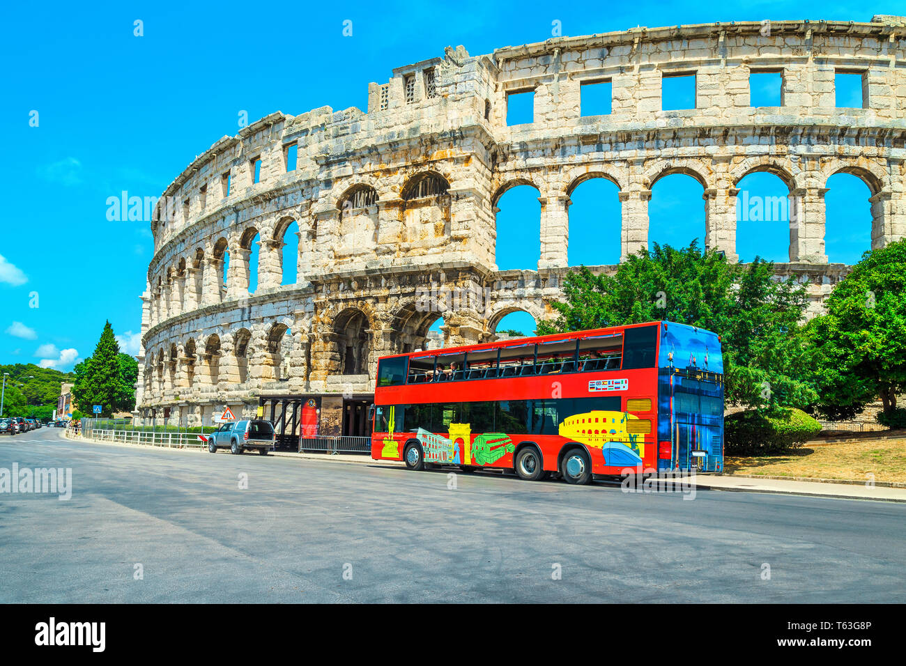Spektakuläre alte historische Gebäude mit bunten Touristische Bus. Blick auf die Straße mit dem berühmten Römischen Amphitheater (Arena) in Pula, Istrien penin Stockfoto