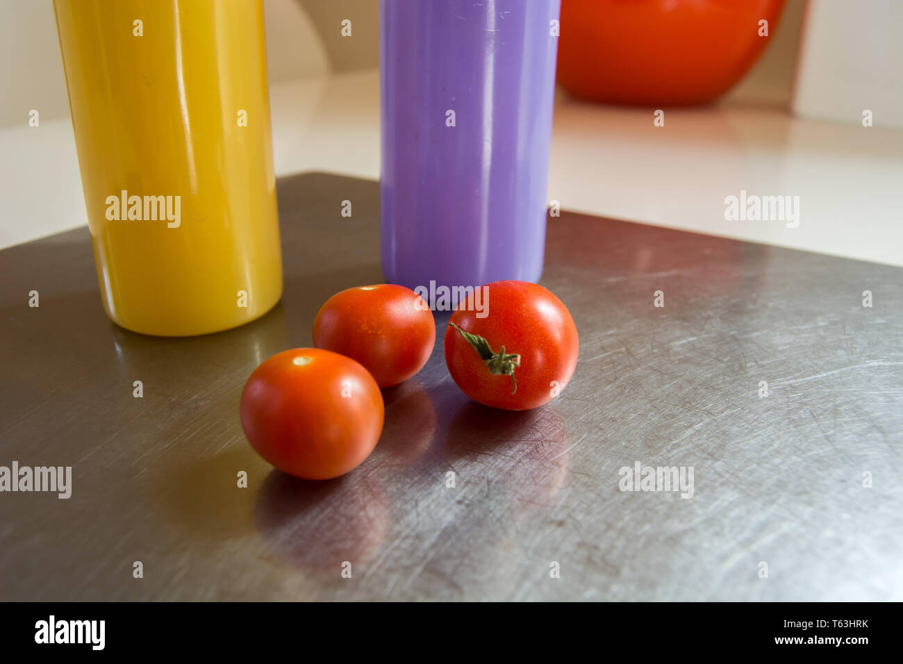 Drei kleine Tomaten liegen auf einer Aluminium- und farbenfrohen speisen Stockfoto