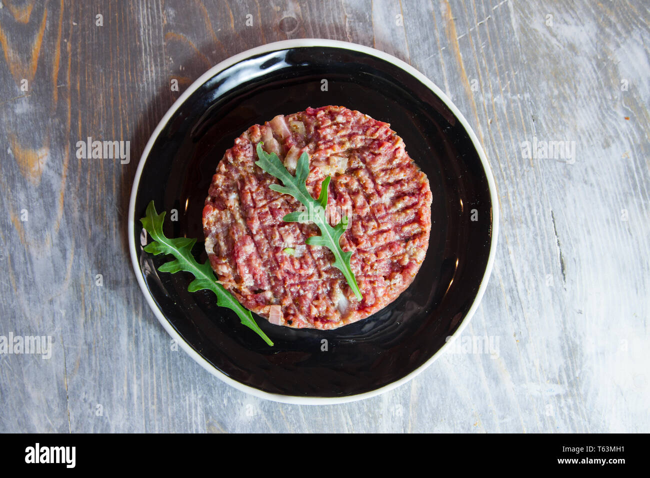 Steak Tartare, schneiden sie in Scheiben geschnitten und mit einem Messer, der Boden Hackfleisch, auf Anzeige auf einem rustikalen Holztisch. Steak Tartar ist ein symbolischer Gericht der F Stockfoto