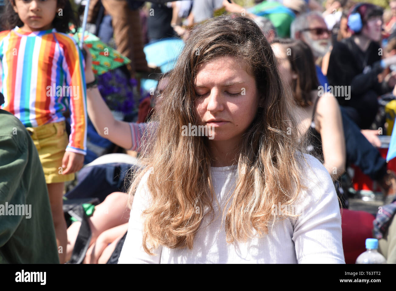 Eine junge Frau meditiert unter den Demonstranten. Aussterben Rebellion Klimawandel protestieren. Waterloo Bridge, London Stockfoto