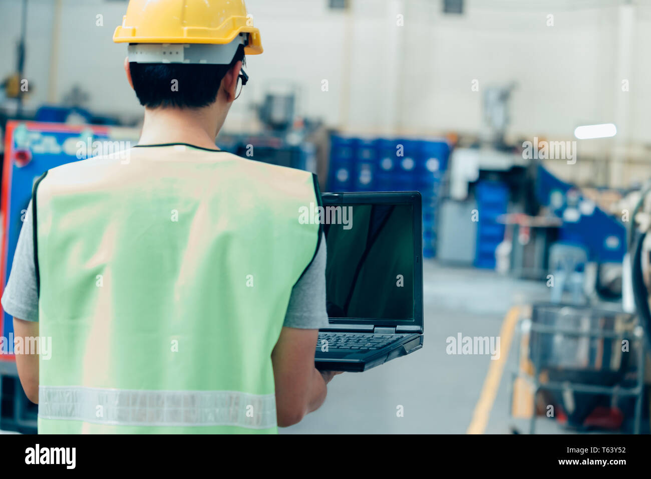 Asiatische männlichen Industrial Engineer in hardhat arbeitet mit Laptop im Safety Jacket in der Schwerindustrie. Verarbeitung Kunststoffspritzerei Industrie Stockfoto