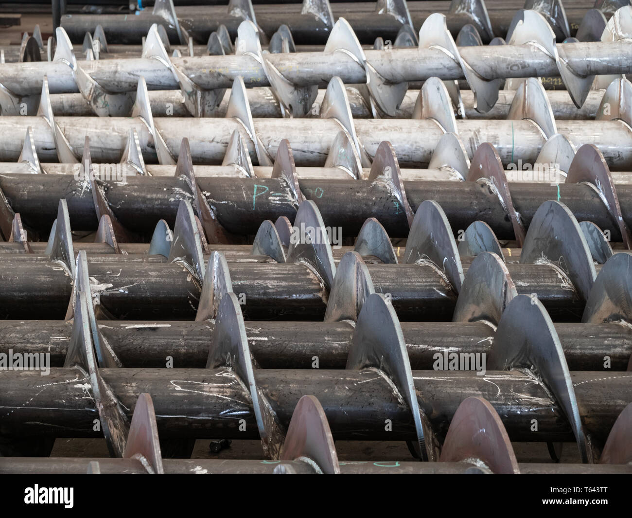 Schrauben für Förderschnecken während der Produktion. Carbon Steel Schrauben im Vordergrund und Schrauben aus Edelstahl im Hintergrund. Stockfoto