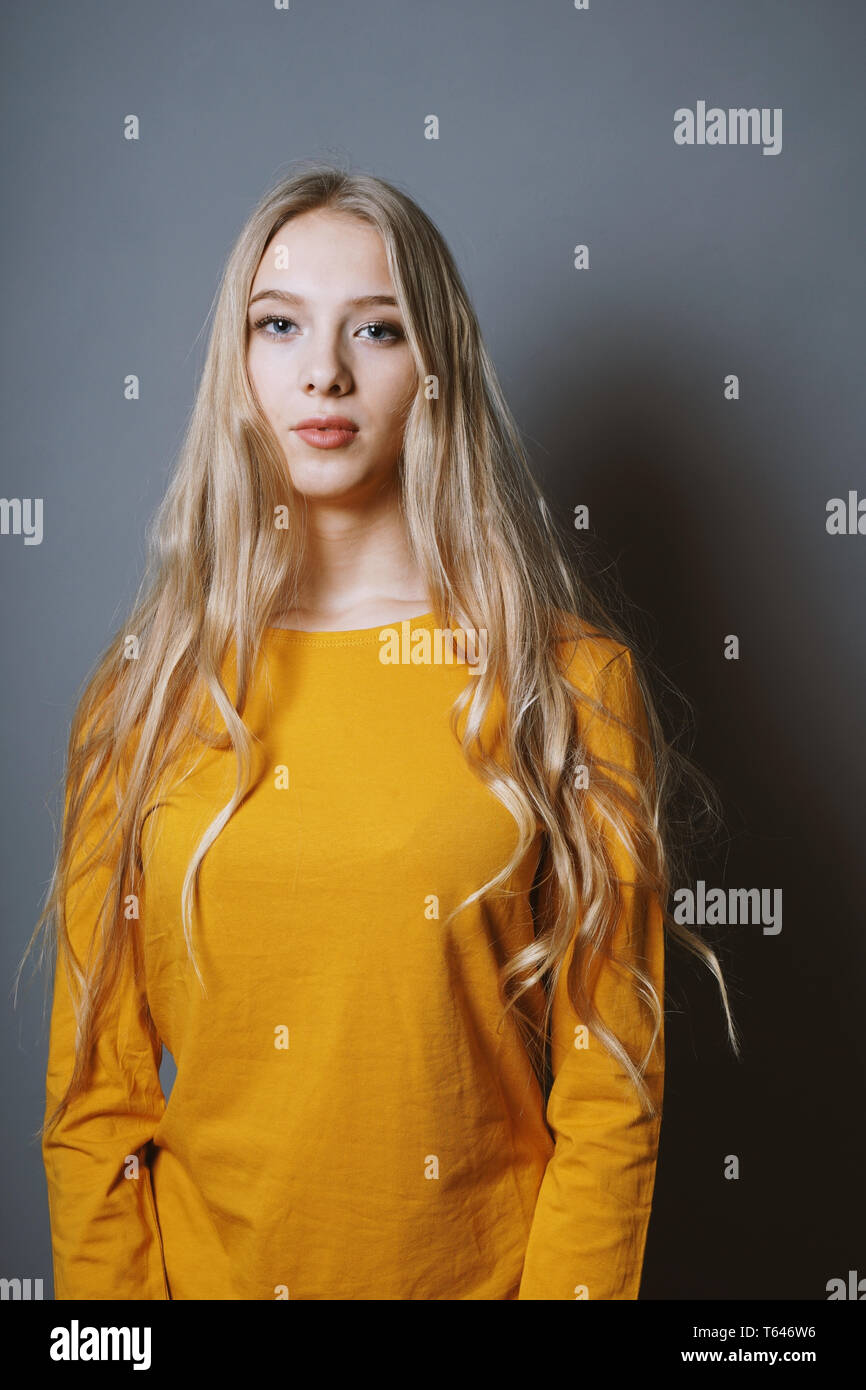 Serene teenage Mädchen mit sehr langen blonden Haare vor grauem Hintergrund Stockfoto