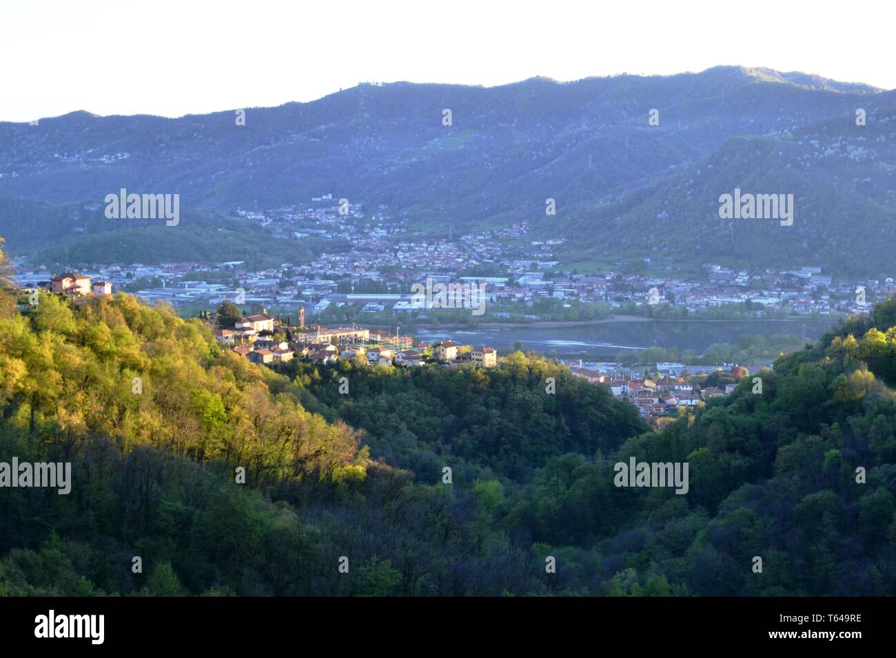 Schöner Panoramablick von der Straße auf den Wald auf hohen Bergen zu Erve, Calolziocorte und Garlate See, Rossino Burg in frühen Abend im Frühling. Stockfoto