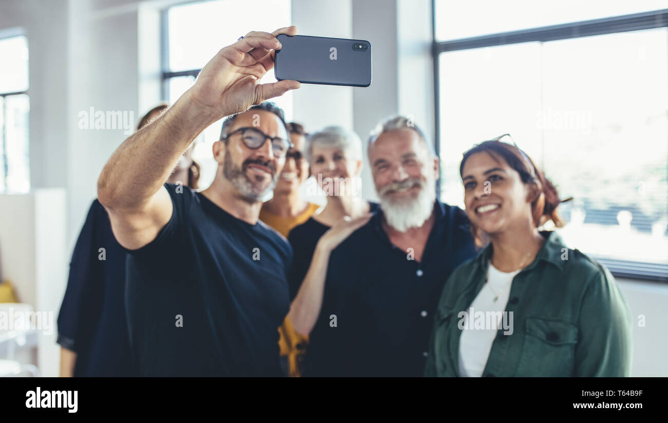 Geschäftsleute machen Selfie von sich im Büro. Erfolgreiches Business-Team, das Selfie bei der Inbetriebnahme zusammen macht. Stockfoto