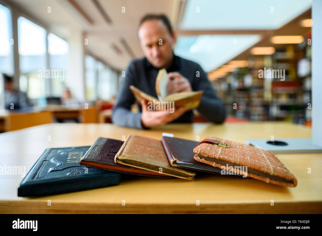 Oldenburg, Deutschland. 11 Apr, 2019. Stefan Walter, wissenschaftlicher Mitarbeiter am Institut für Pädagogik an der Carl-von-Ossietzky-Universität in Oldenburg, sitzt in einer Bibliothek und betrachtet ein Poesie Album. Walter hat recherchiert und seine Dissertation über Poesie Alben geschrieben. Credit: mohssen Assanimoghaddam/dpa/Alamy leben Nachrichten Stockfoto