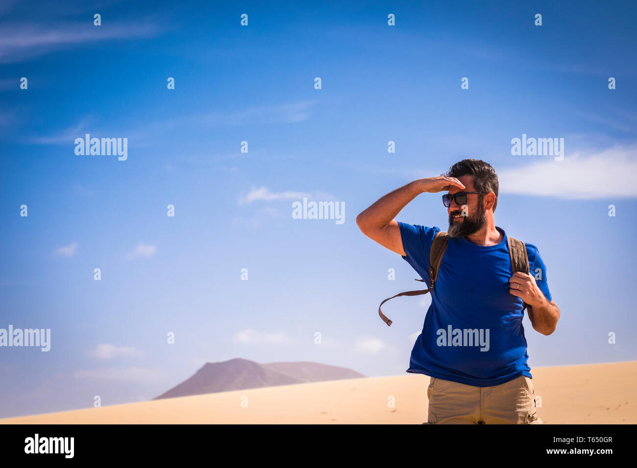 Backpacker lifestlye Menschen mit kaukasischen erwachsenen Mann suchen, Reisen mit einem Rucksack in den Dünen der Wüste mit Bergen und blauem Himmel Stockfoto