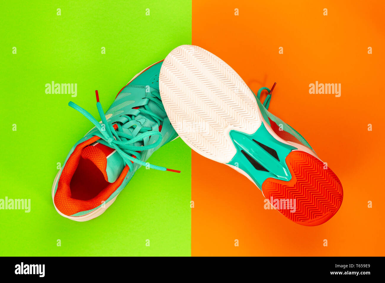Rot, hellblau, weiß, Paar neue Tennisschuhe im Studio Schuß über grün, orange Hintergrund. Direkt von oben. Stockfoto