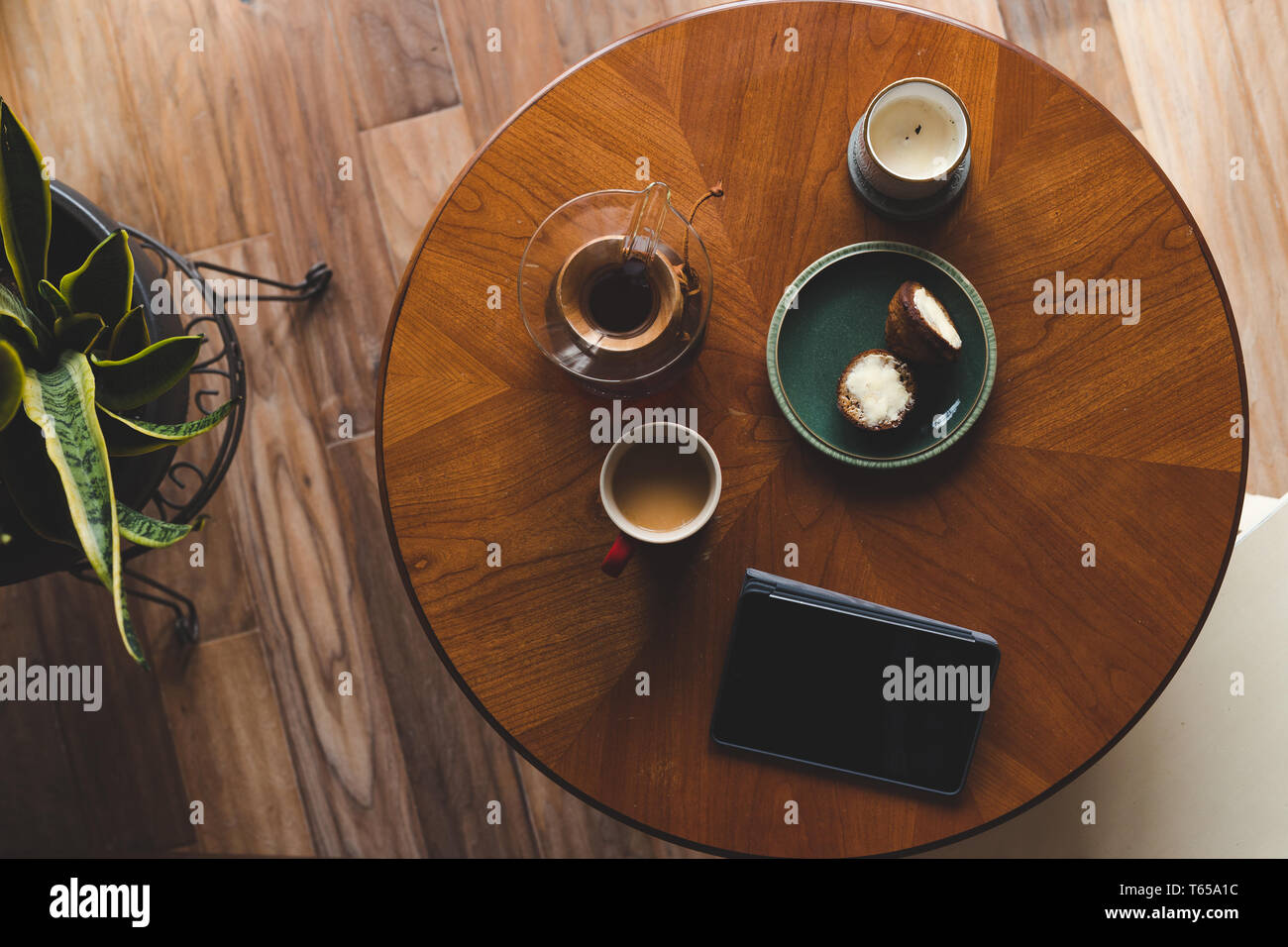 Eine Top-down Shot der modernen Wohnzimmer Couchtisch mit einer Kaffeetasse, Buch, Tablet-PCS und einen Muffin. Stockfoto