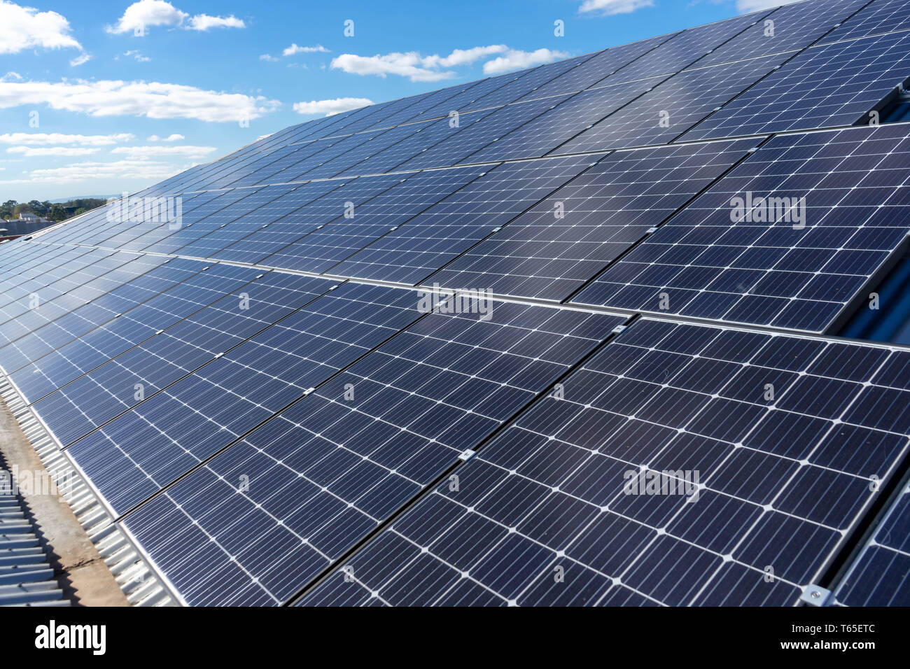 Solarzellen auf einem Dach mit blauem Himmel und weißen Wolken Hintergrund Stockfoto