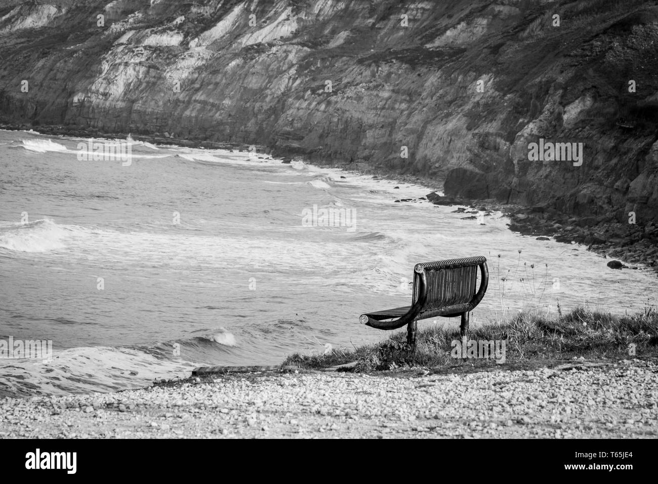 Schwarz-weiß Foto von Landschaft am Meer mit einsamen, leeren Bank. Stockfoto