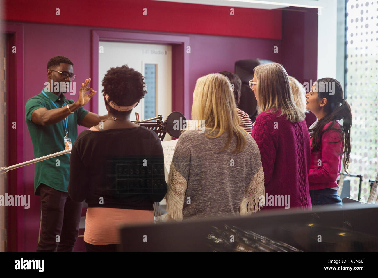 Männliche Leiter führenden Frauen singen in Music Recording Studio Stockfoto