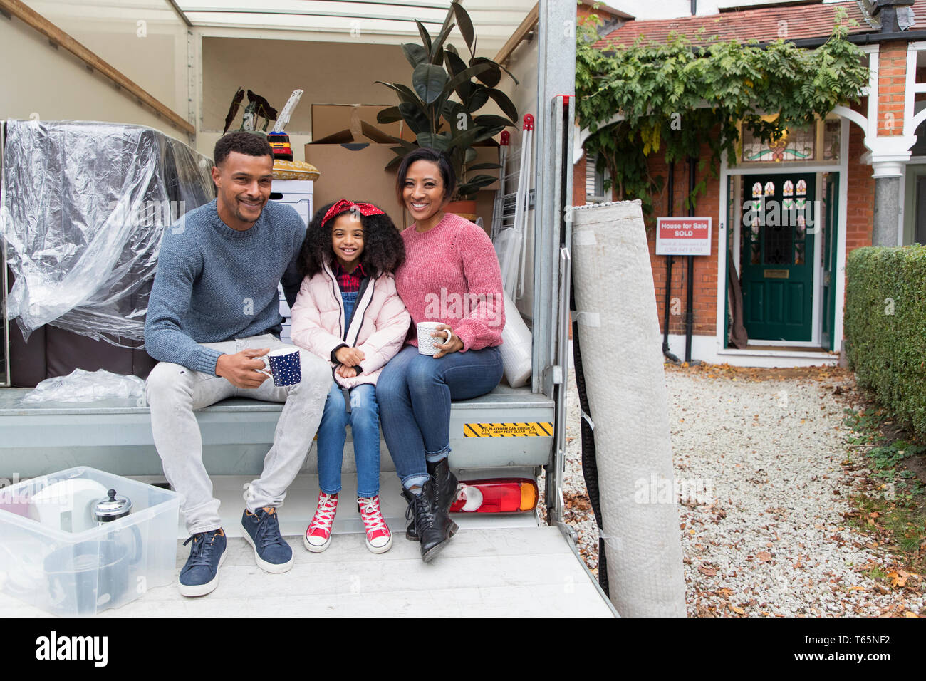 Portrait happy family Tee trinken an der Rückseite des Moving van außerhalb neues Haus Stockfoto