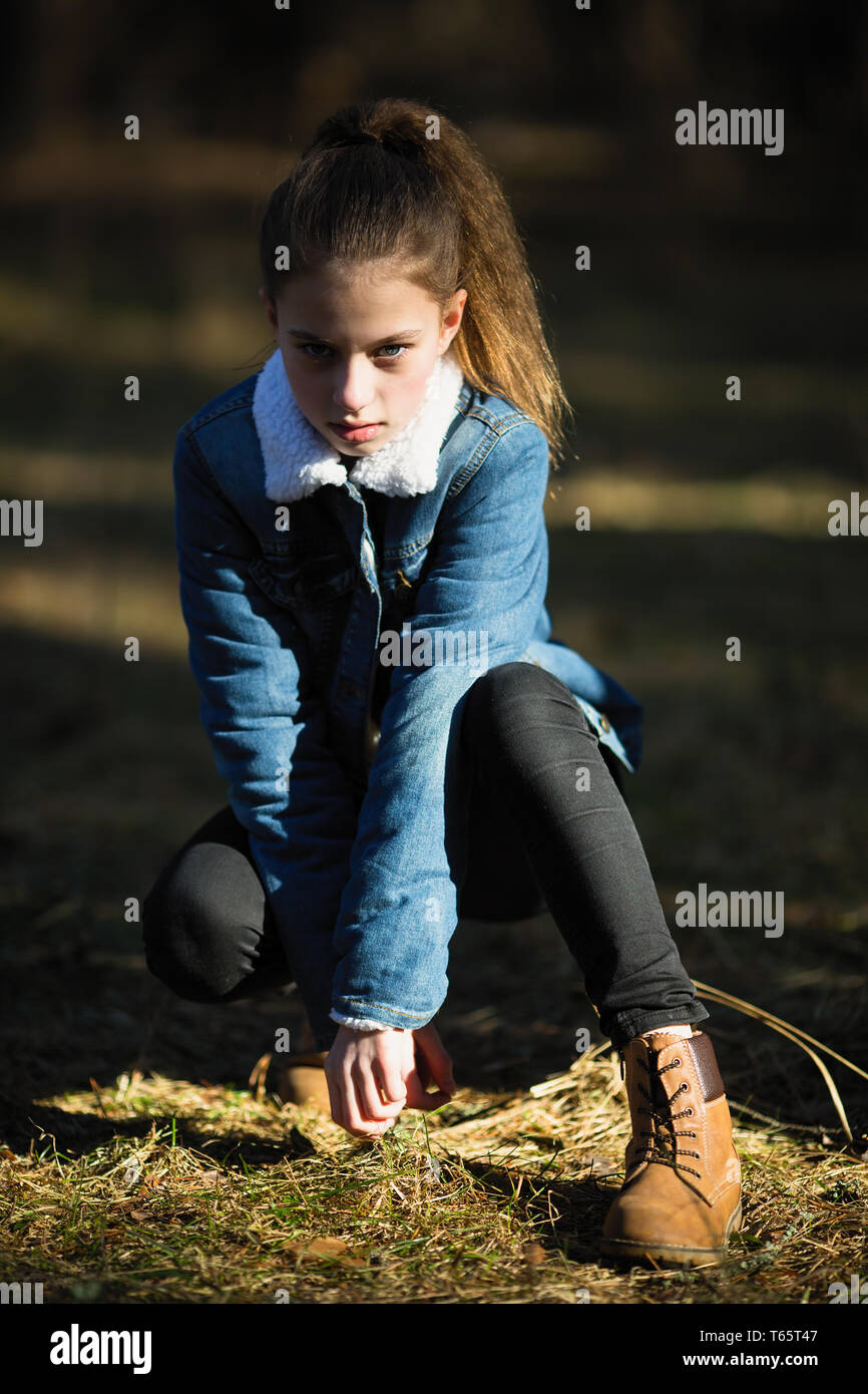 11-jährige Mädchen in einem Jeansjacke für die Kamera in einem Pinienpark  posieren Stockfotografie - Alamy