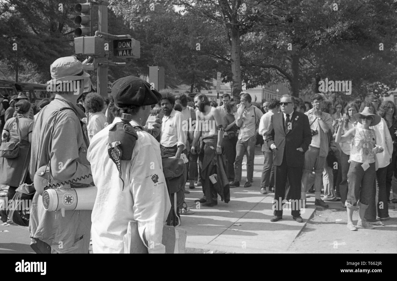 Ein Mann in Anzug und Krawatte, und zwei Männer, die mit Dokumenten und ein Megaphon, stand inmitten einer Menge von Demonstranten während der Kent State/Kambodscha Einfall Protest, Washington, District of Columbia, 9. Mai 1970. () Stockfoto