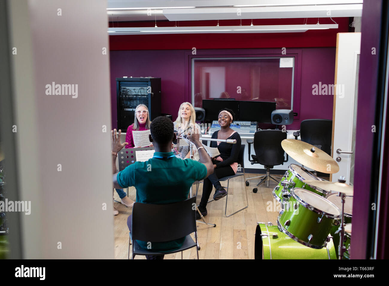 Männliche Leiter führenden Frauen singen in Music Recording Studio Stockfoto