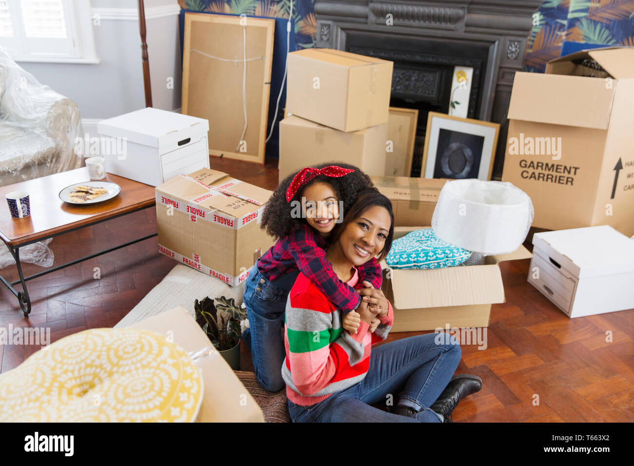 Portrait glücklich, liebevolle Mutter und Tochter umarmen unter Kartons, Umzug Stockfoto