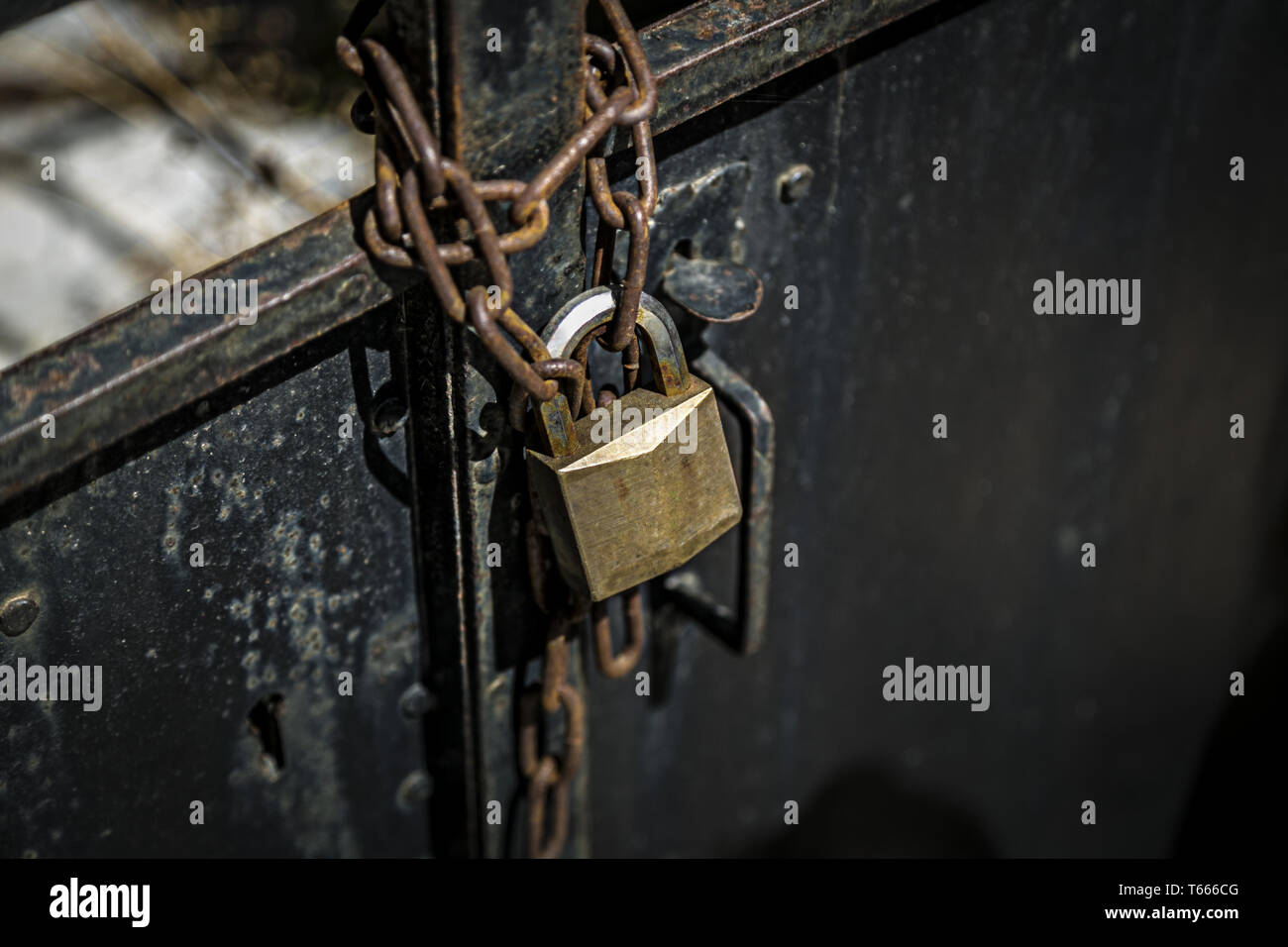 rostige Kette auf einer Metalltür mit Vorhängeschloss Stockfoto