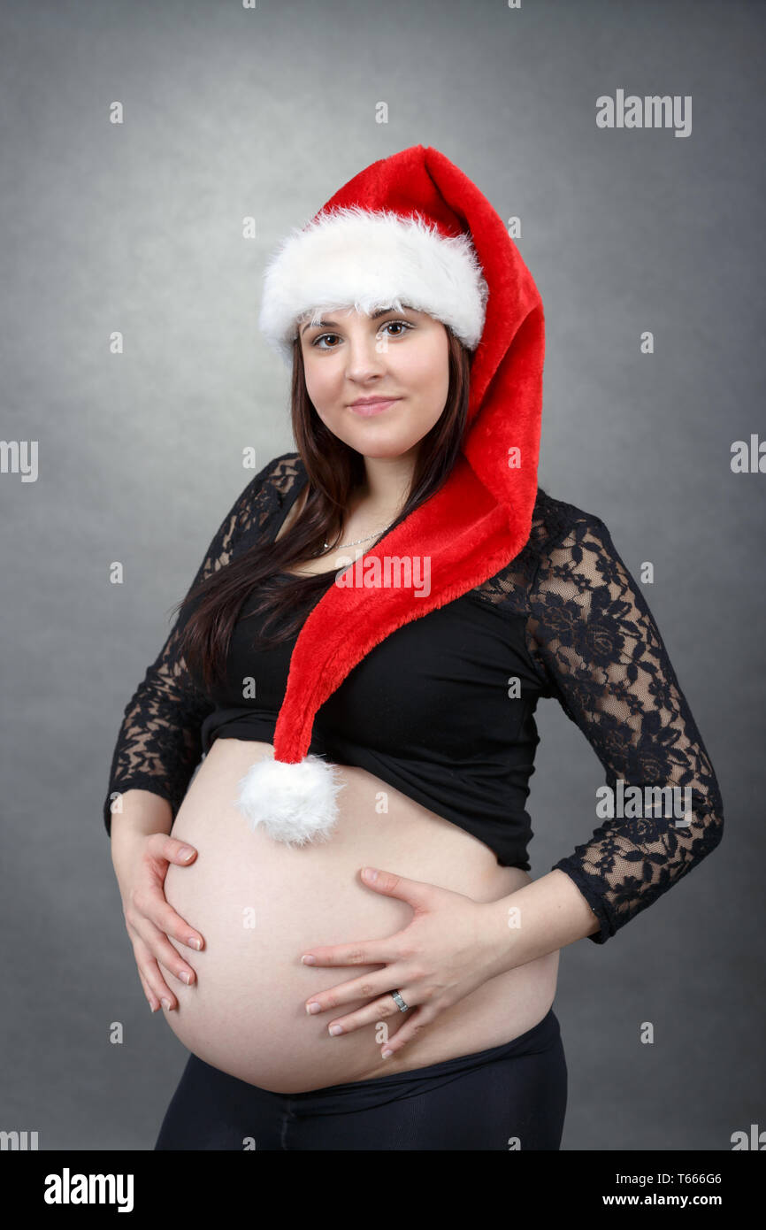 Schöne schwangere santa Frau zärtlich ihren Bauch Holding Stockfoto
