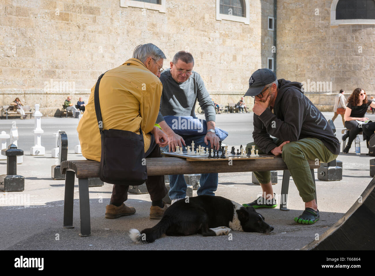 Schachspiel, Blick auf Männer mittleren Alters, die eine Schachpartie auf dem Kapitelplatz in Salzburg, Österreich, spielen. Stockfoto