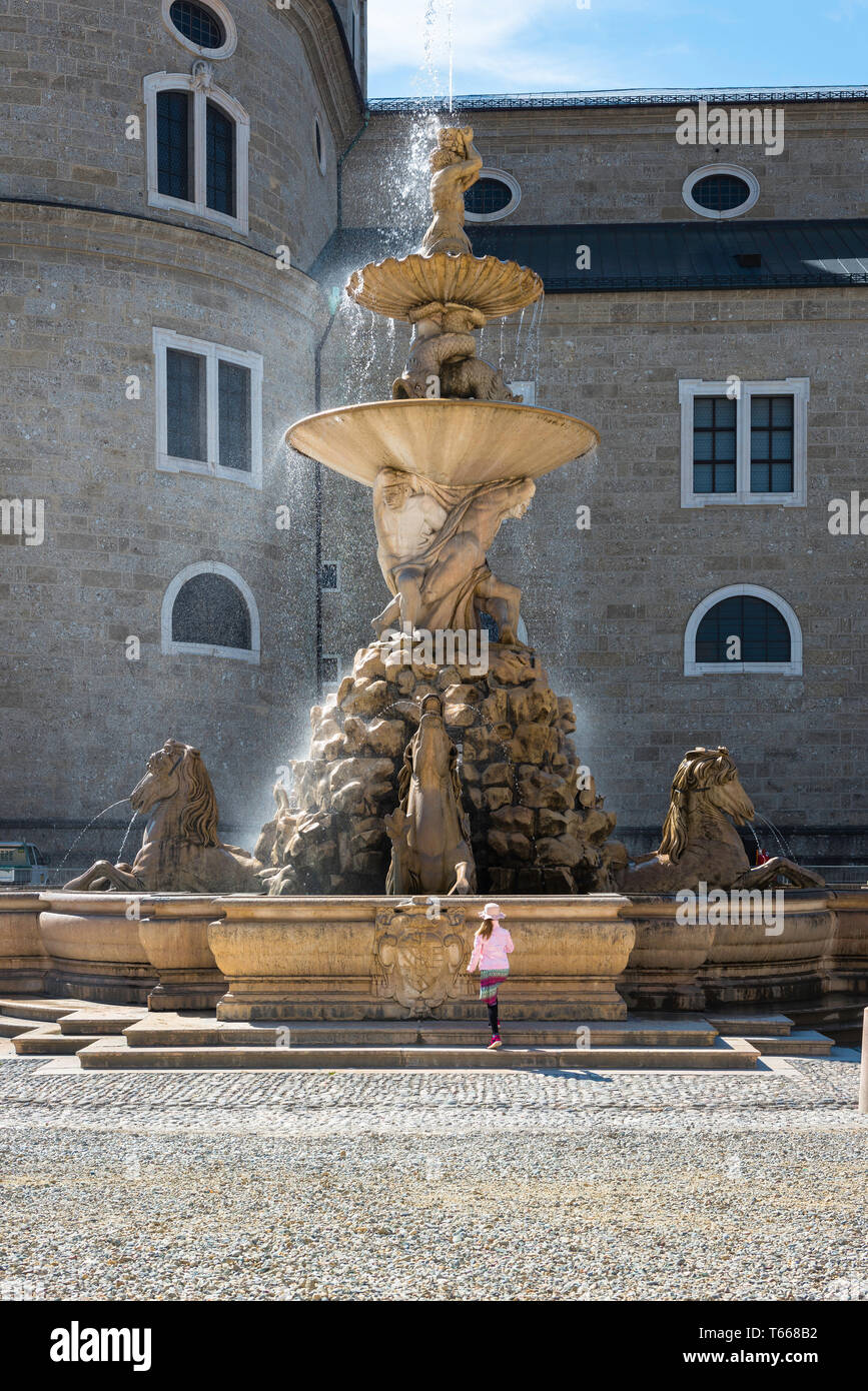 Salzburg, Residenzplatz Brunnen Blick eines Kindes nähert sich der barocke Brunnen auf dem Residenzplatz in Salzburg Altstadt, Österreich gelegen. Stockfoto