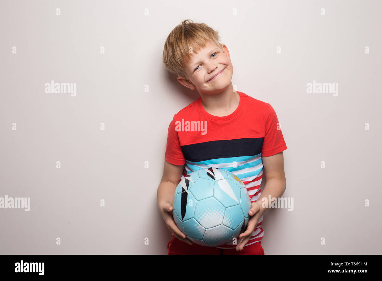 Süße kleine Junge stehend mit Fußball und Kamera. Auf weiß isoliert. Studio Portrait Stockfoto