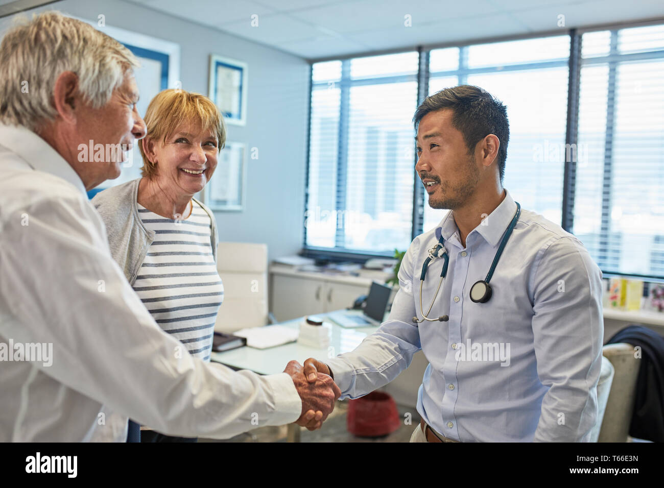 Männlicher Arzt Händeschütteln mit Senior Paar in Klinik Ärzte Büro Stockfoto