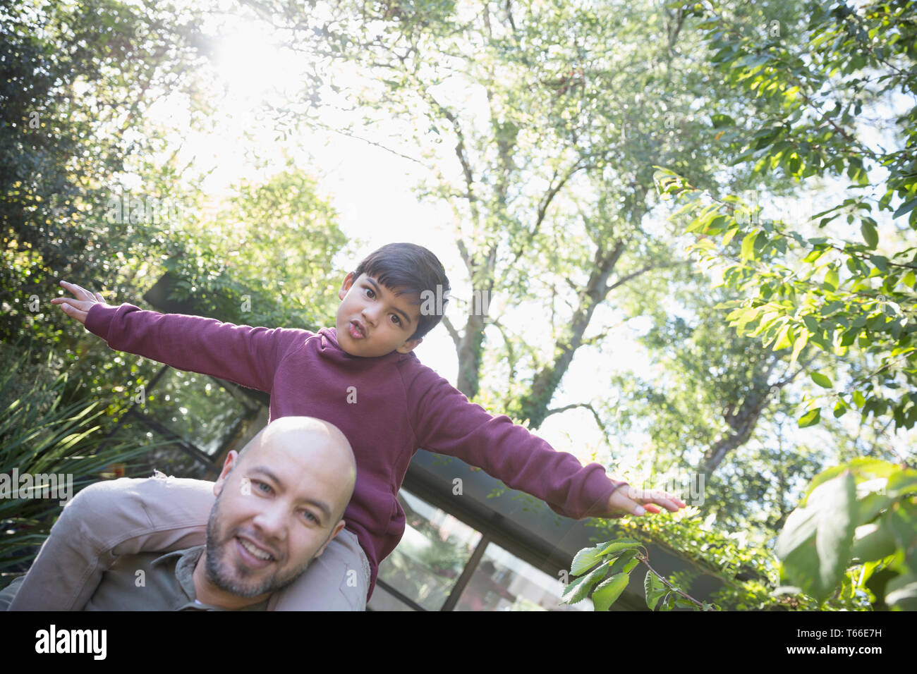 Portrait verspielt Vater mit Sohn auf den Schultern im Hinterhof Stockfoto