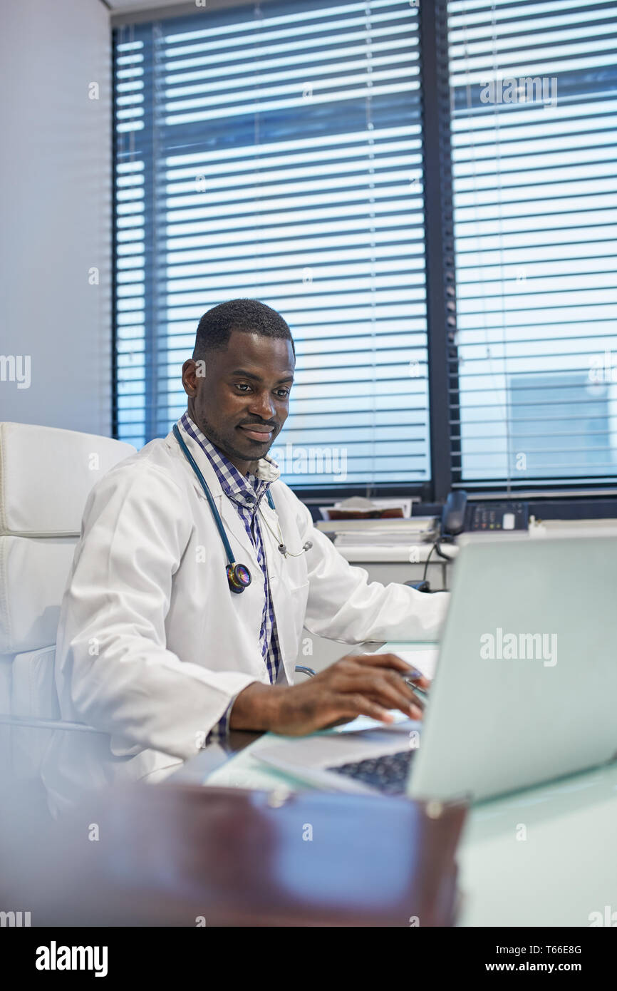 Männlicher Arzt am Laptop arbeiten im Doktorbüro Stockfoto