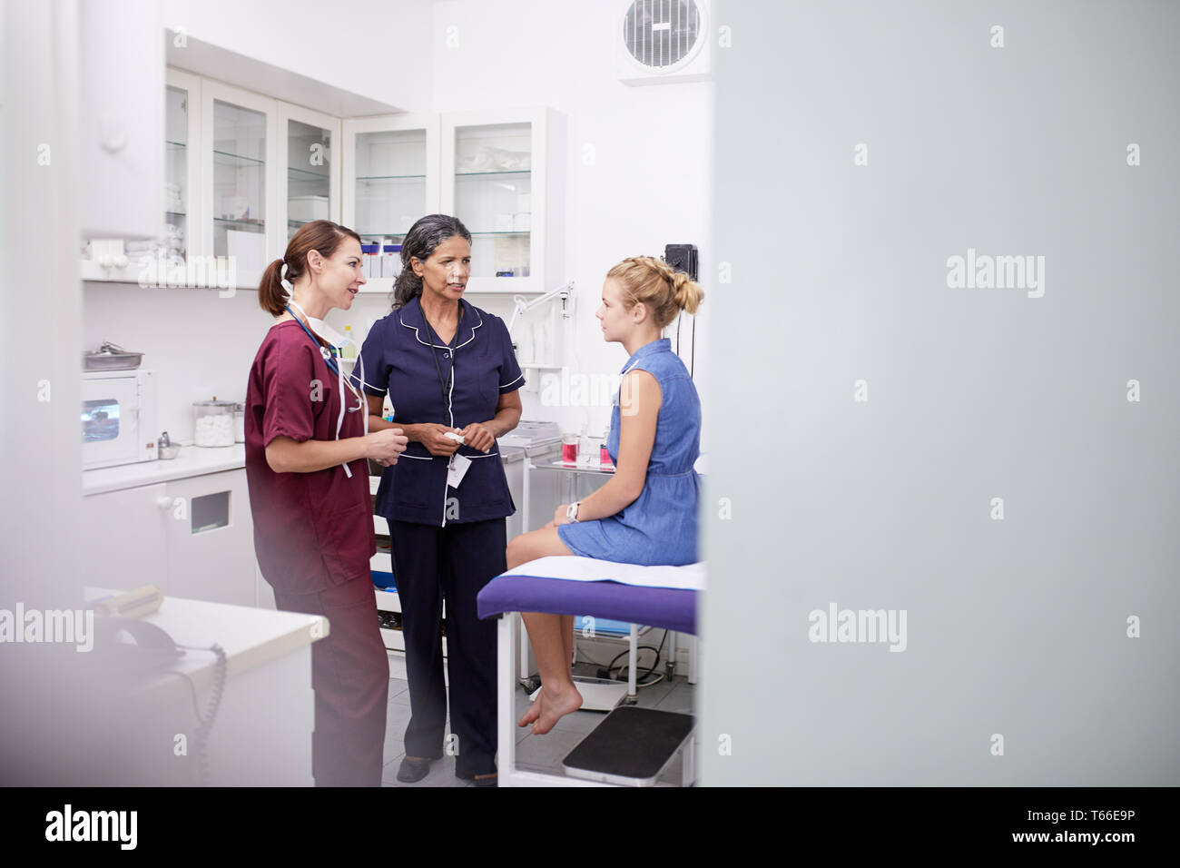 Frau Doktor und Krankenschwester im Gespräch mit Mädchen Patienten in Klinik Untersuchungsraum Stockfoto