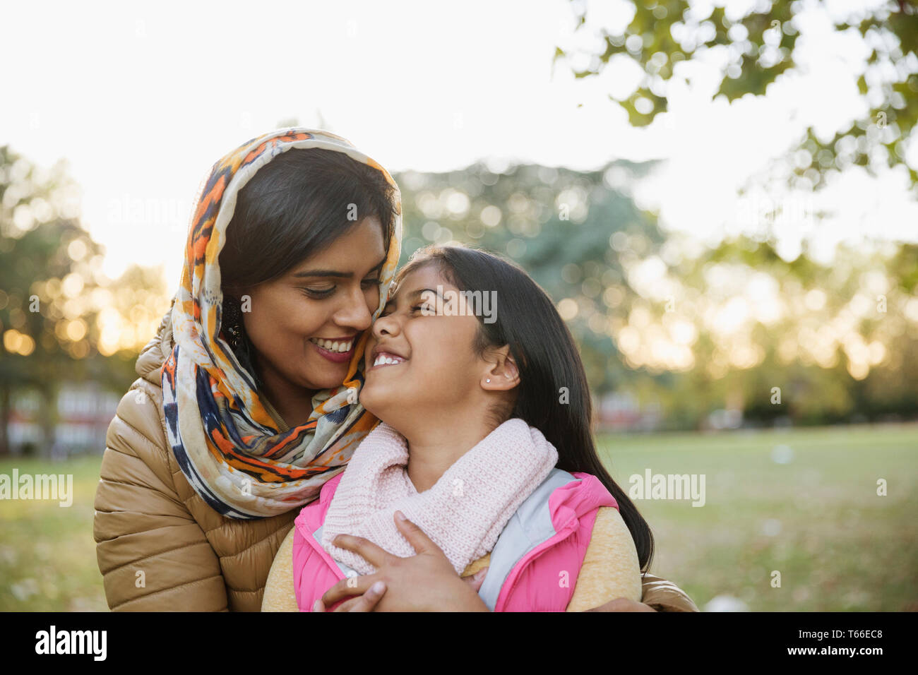 Zärtlich, glücklich muslimische Mutter im hijab umarmen Tochter im Herbst Park Stockfoto