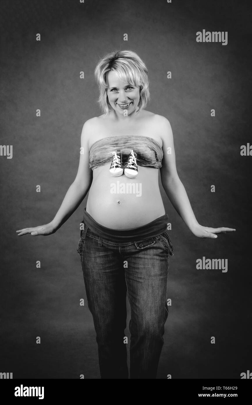 Schöne schwangere Frau mit Kind Stiefel auf ihrem Bauch Stockfoto