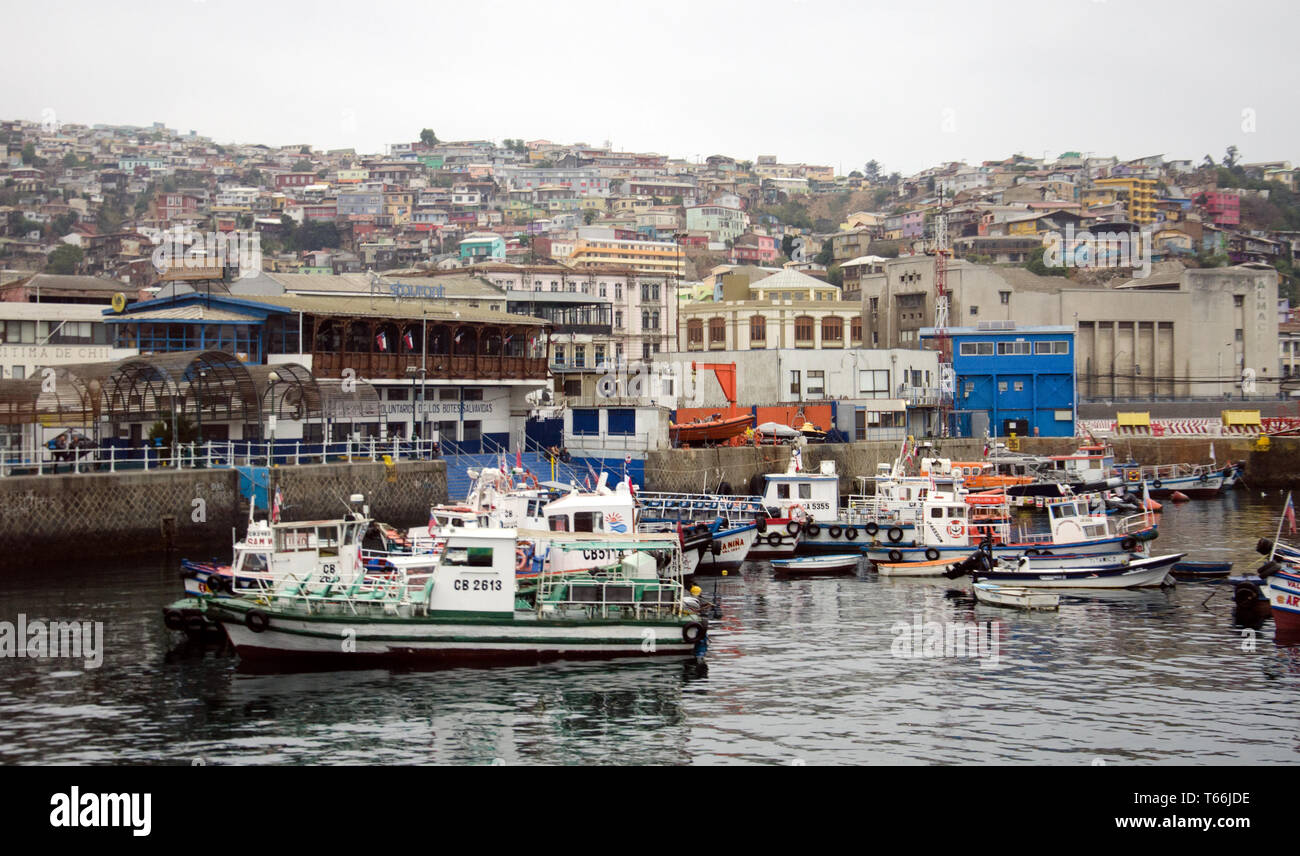 Kleine und mittlere Boote im Hafen im historischen Hafen von Valparaiso in Chile; die Stadt liegt am Hang über Stockfoto