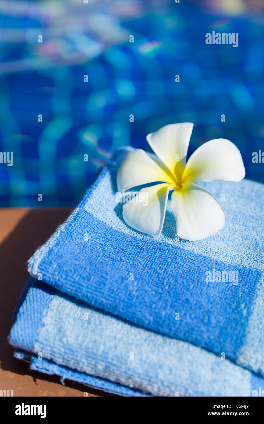 Flauschige blaue Handtuch mit plumeria frangipani Blume an der Grenze von einem Pool Stockfoto