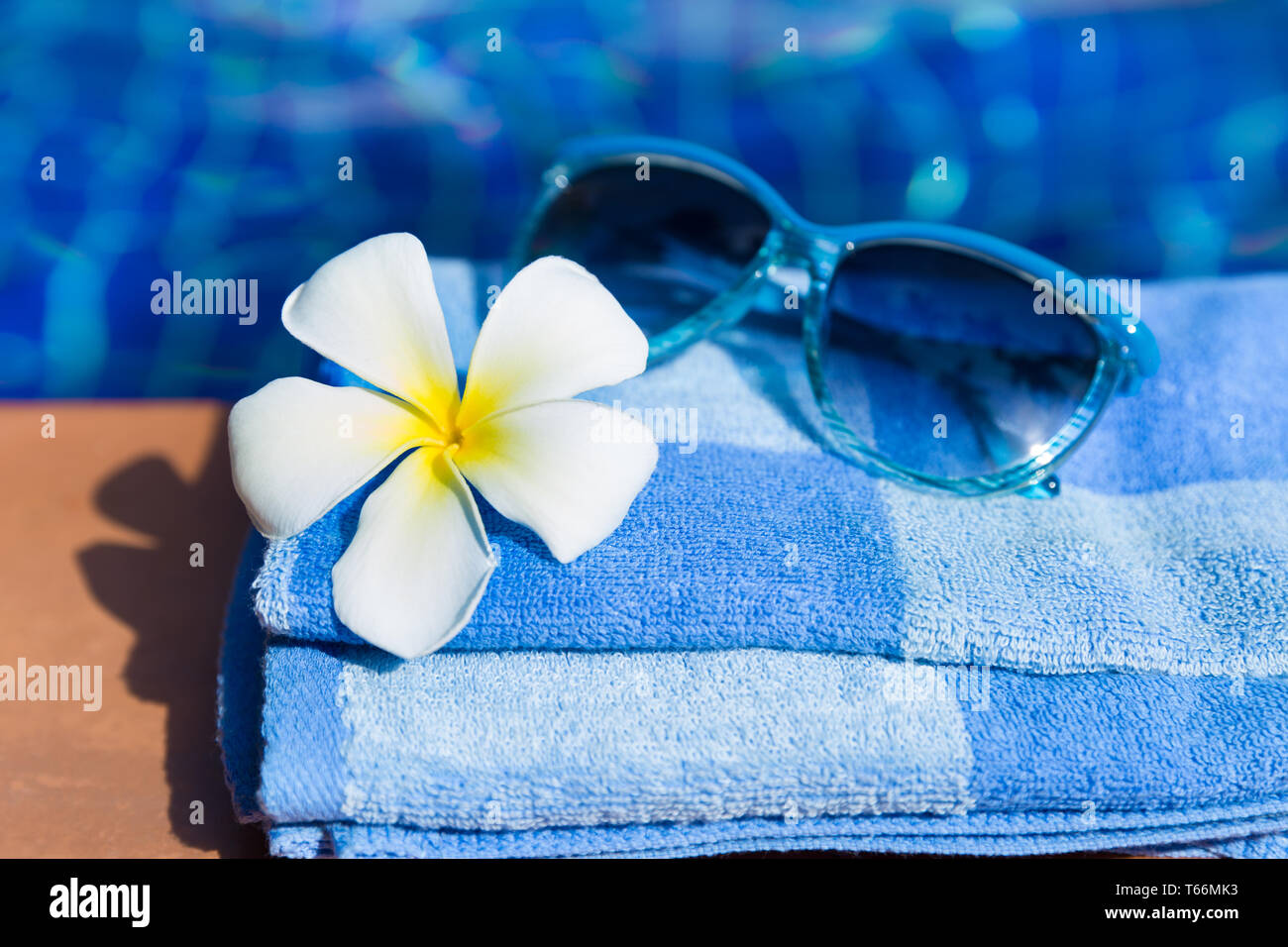 Flauschige Handtuch mit Sonnenbrille und Blume an der Grenze von einem Pool Stockfoto