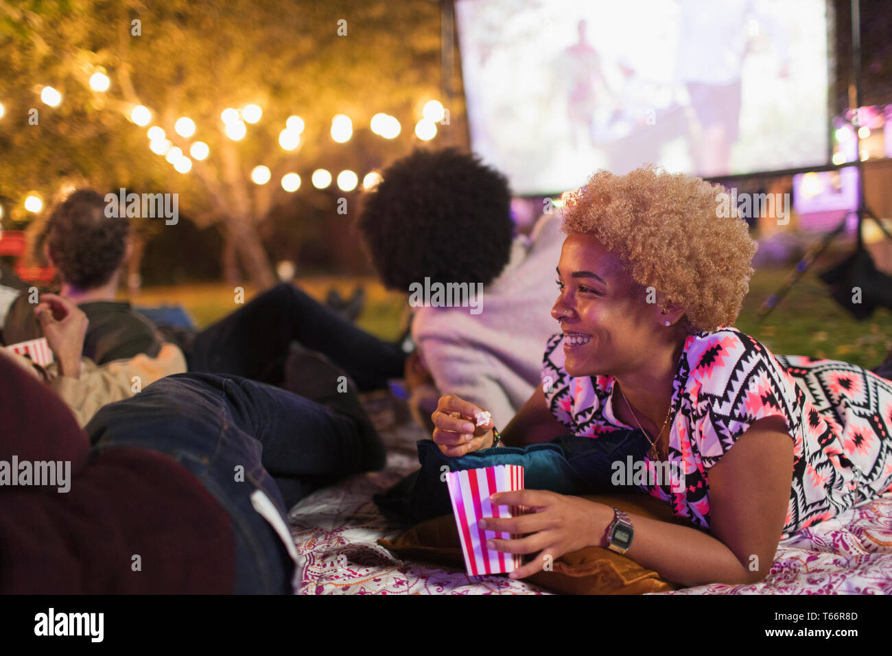 Glückliche Frau essen Popcorn, watching Film mit Freunden im Hinterhof Stockfoto