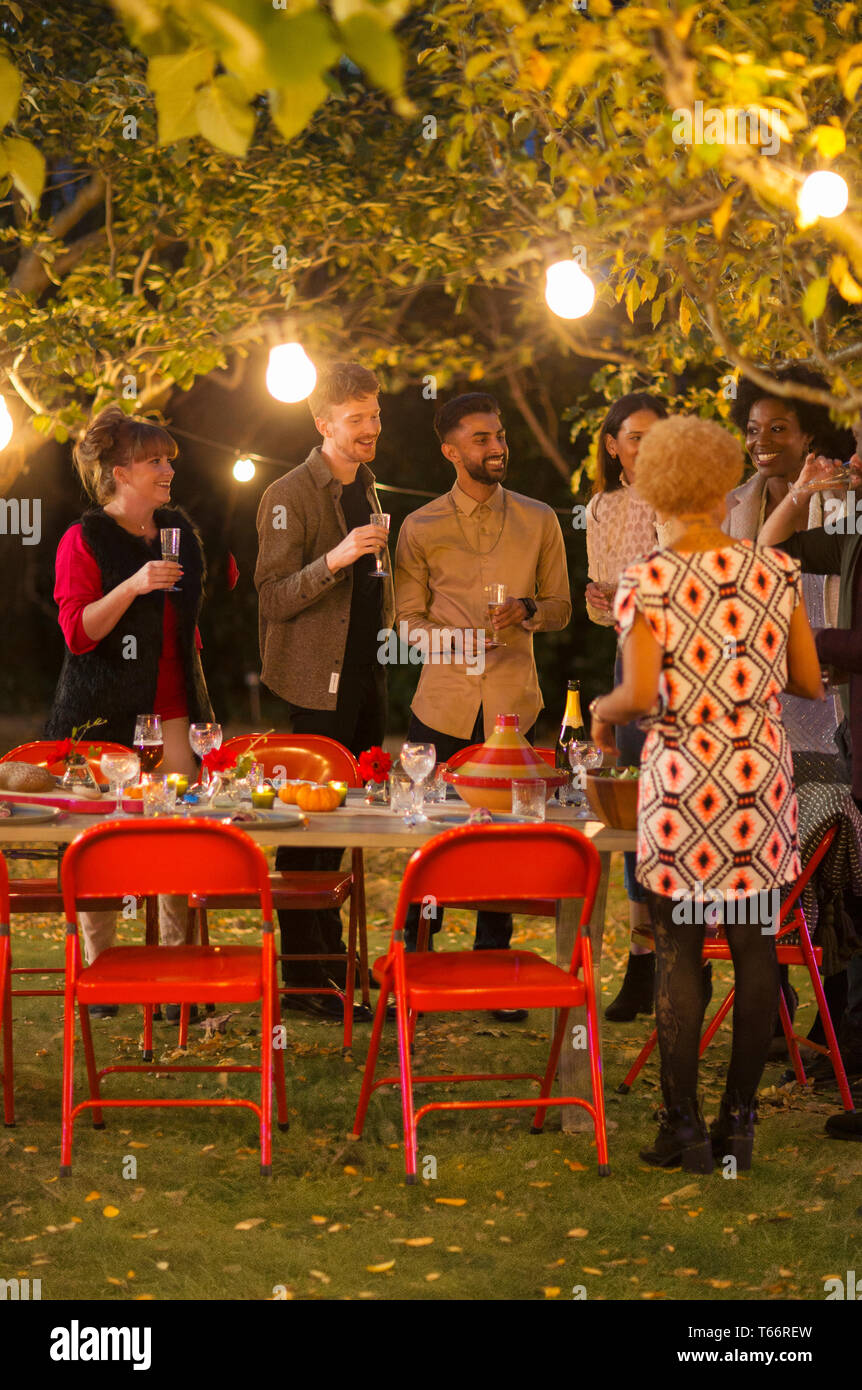 Freunde sprechen unter Bäumen am Abendessen Garden Party Stockfoto